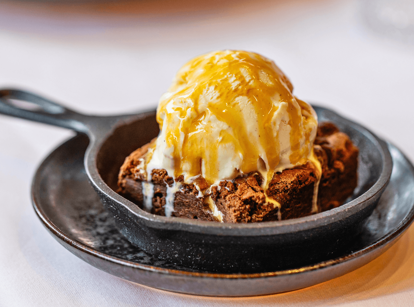 a chocolate brownie dessert with ice cream gently melting on top