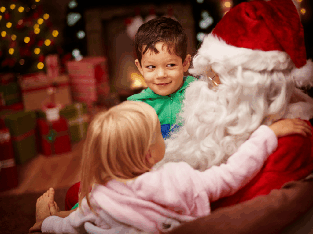 Two young kids sitting on Santa's lap tell christmas wishes