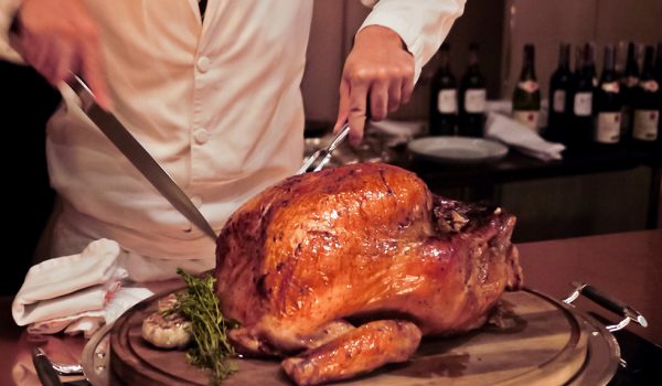 Professional chef carves a whole, roasted Turkey. An impressive centerpiece for family party, Easter, Thanksgiving, Christmas and New Year celebration. Festive holiday and season greeting. Warm light.